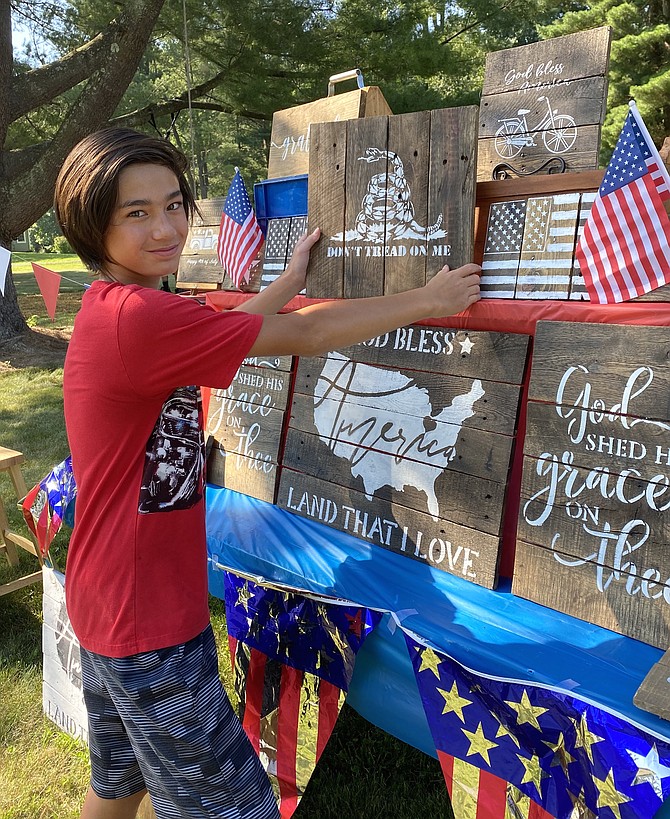 Joey Newton, 13, of Great Falls, owner of 'Joey's Wood Signs' sets up a display table with his handcrafted rustic signs made with reclaimed lumber.