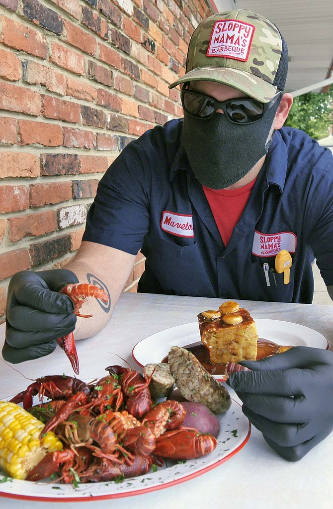 Joe Newman pulls the tail off a crawfish boiled in a 20-gallon pot of water with potatoes and corn and his own “happy sprinkles” BBQ rub. “It’s all about grinding your own spices, and the ratio makes it what it is.”