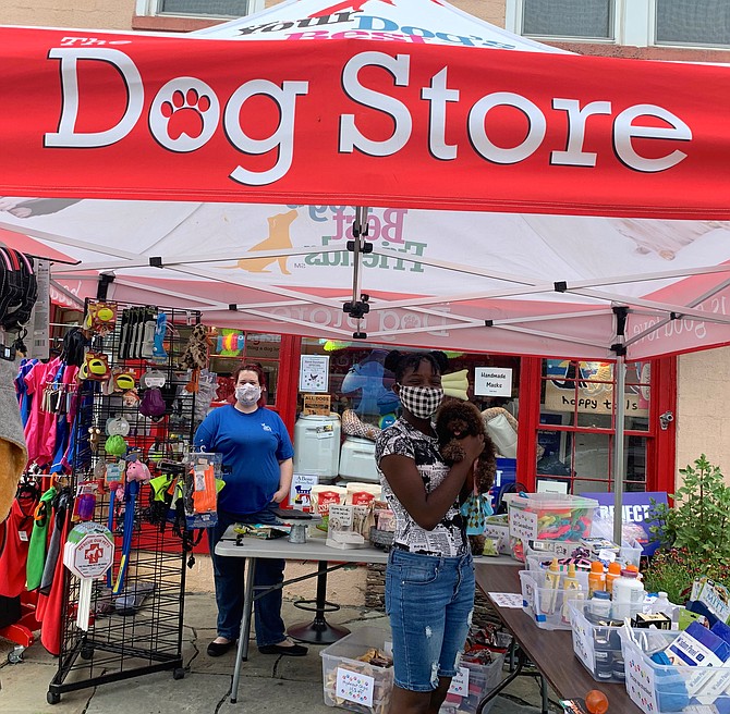 Sales associate Annabelle Bivens, left, looks on as Aniya Witherspoon holds Cocoa Love outside the Dog Store during the Aug. 16 sidewalk sale in Del Ray.