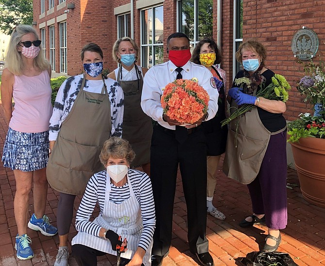 Alexandria Fire Chief Corey Smedley, third from right, holds a flower basketball from Hunting Creek Garden Club and Garden Club of Alexandria members Jackie Locke, Amy Bertles, Lynn Gas, Margaret Gardner, Starlet Zarek and Laura Francis during a “flower flashing” at Charles Houston Recreation Center.