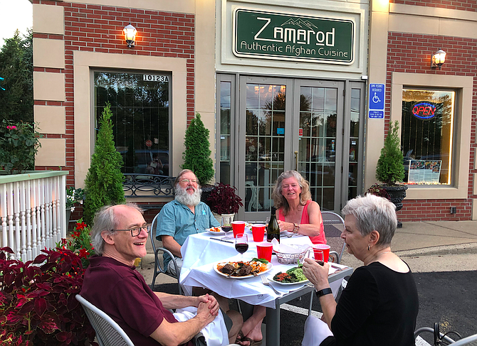 Two couples enjoy a socially-distanced Thursday evening meal in front of Zamarod. “We love this kind of food, and we love the owner,” said Sue Holberger (back right).