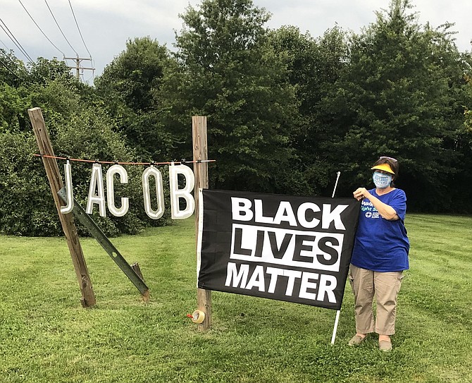 Protestor Nancy Howe Despeaux holds a Black Lives Matter flag. The leftmost sign reads “JACOB,” in reference to the police shooting of Jacob Blake, a Black man, in Kenosha, Wis. several days before.