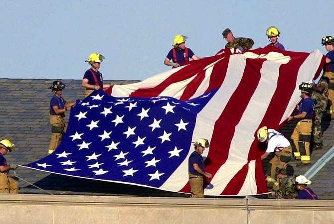 Lt. Jim Morris, far bottom right, and fellow firefighters from Alexandria and Fairfax County Fire and Rescue join soldiers atop the Pentagon to unfurl an American flag during rescue and recovery efforts Sept. 12, 2001. Morris’s brother Seth perished in the attacks on the World Trade Center.