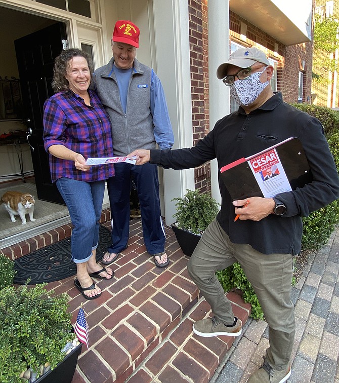 Karen and Paul Novak, voters in the Town of Herndon, take a campaign door hanger from Council member candidate and incumbent Cesar del Aguila. Charlie, the kitty, is all ears.