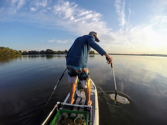 Off the shore in Mount Vernon, Joe Wright scans the river bank for trash within sight of the Mount Vernon Estate.