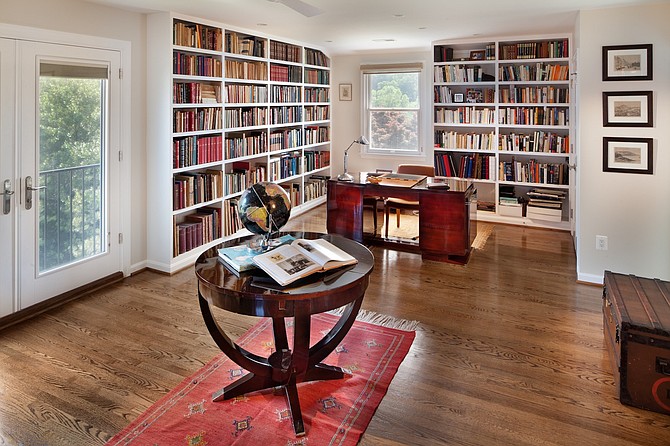 A desk and floor-to-ceiling bookcases allow this space by Keira St. Claire to function as both a library and home office.