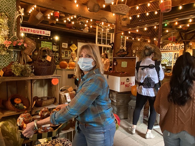 Vendor Ginger Mahon readies her booth at Krop’s Vintage Market Place as patrons line up to pay for their purchases.