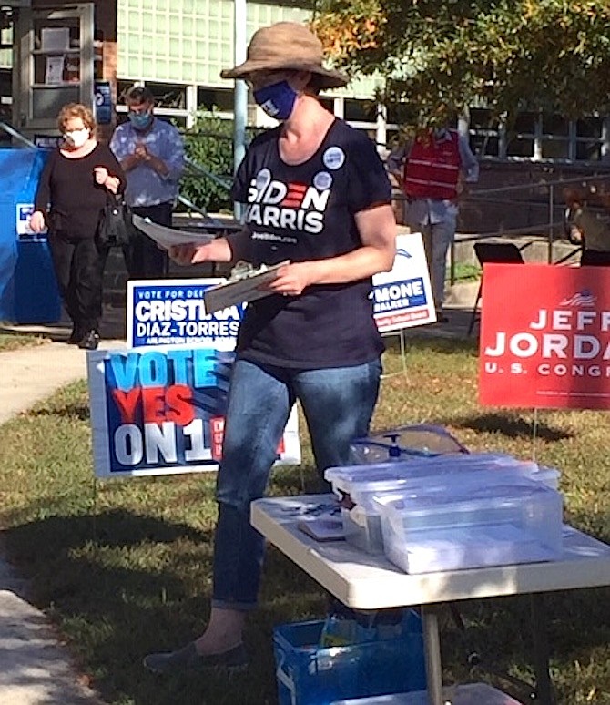 Twelve days left until Election Day and early voting is steady on Thursday, Oct. 22 at Madison Community Center, one of Arlington’s early voting centers. Volunteers working outside the building and election officials inside the balloting site are wearing masks, and cardboard bins sit beside the door for returning pens used to mark ballots.