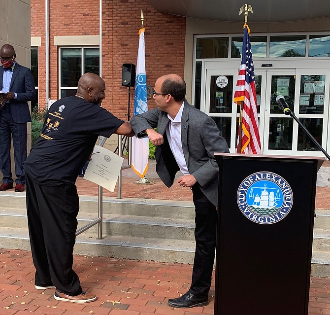 Mayor Justin Wilson, right, gives an elbow bump greeting to Julian “Butch” Haley Jr, chairman of the Alexandria African American Hall of Fame, following the presentation of a proclamation commemorating the 100th anniversary of Parker-Gray School Oct. 24 at Charles Houston Recreation Center.