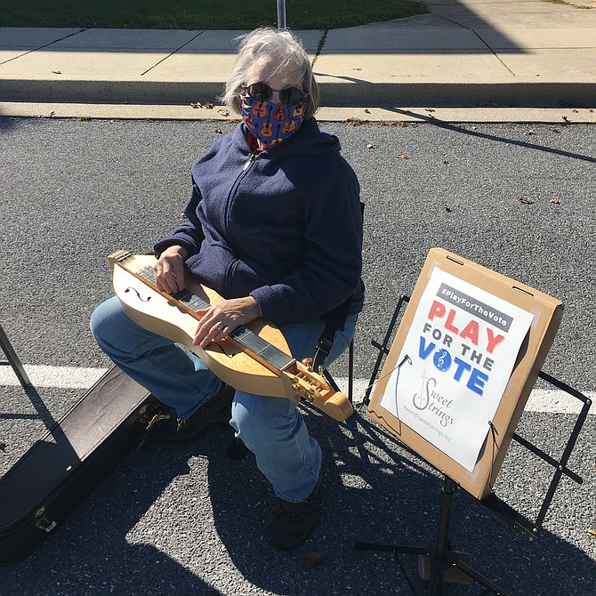 Potomac resident Karen Buglass plays her mountain dulcimer in front of the polls at Winston Churchill High School Tuesday as part of the national Play for the Vote program.