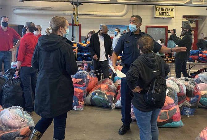 Fairfax County Fire and Rescue Battalion Chief Willie Bailey gives instructions to volunteers at the Oct. 29 Firefighters and Friends coat distribution at Penn Daw Fire Station 11.