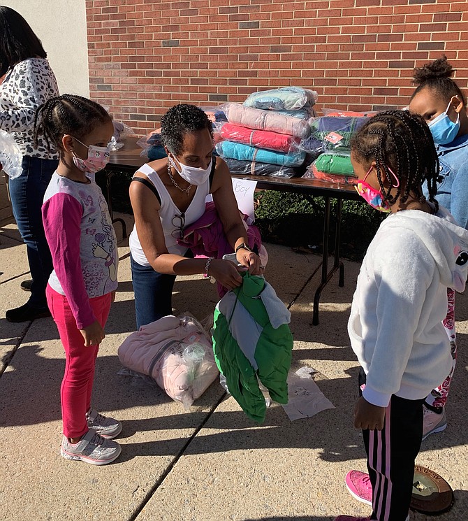 Volunteer Natalie Kimble unwraps a new coat as part of the Firefighters and Friends coat drive distribution at Oakland Baptist Church Nov. 7.