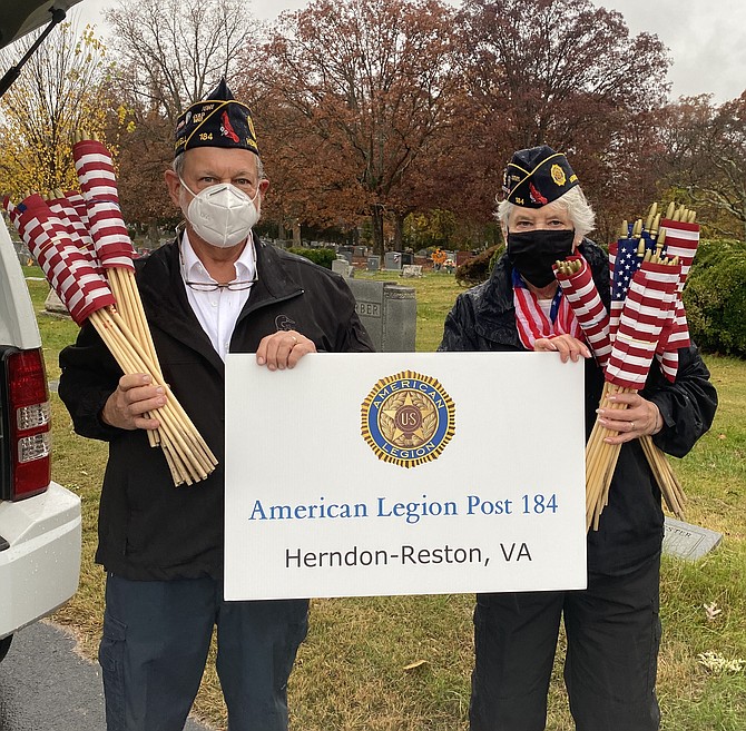 On behalf of The Wayne M. Kidwell American Legion Post 184 Herndon-Reston, Michael Cutler, Vice Commander, and Christine Cutler, Post Adjunct, prepare to install a modified Avenue of Flags.