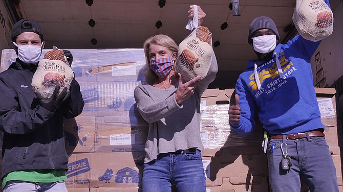 Alias Santiago, Jolie Smith and Ray Bynum open a cardboard box to inspect three of the 2,500 frozen turkeys ordered by AFAC for Thanksgiving dinners for their clients.