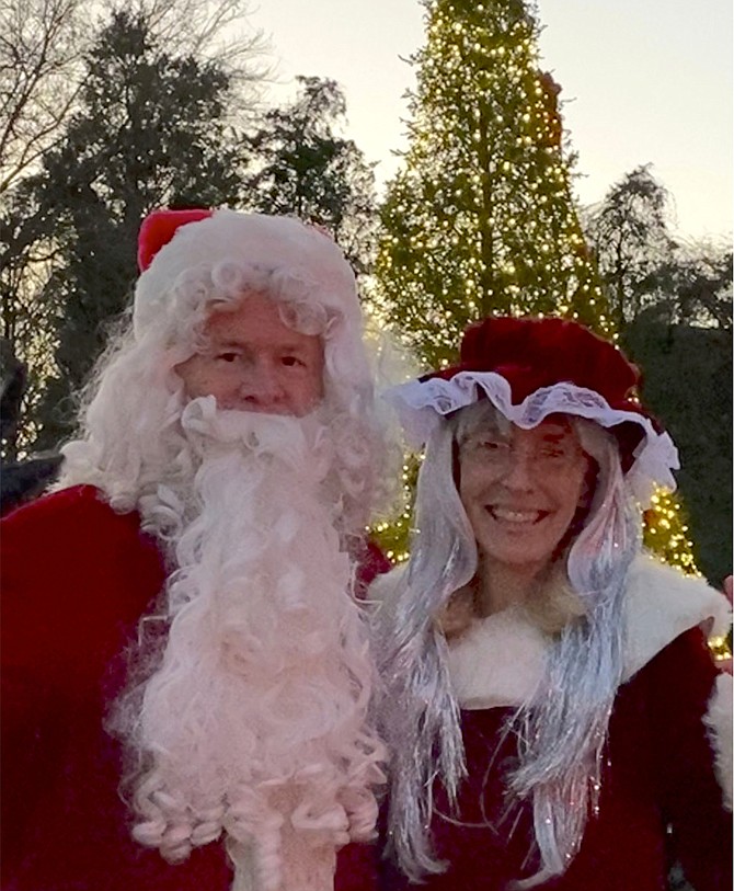 Santa and Mrs. Claus turn around to face their elves after lighting the tree.