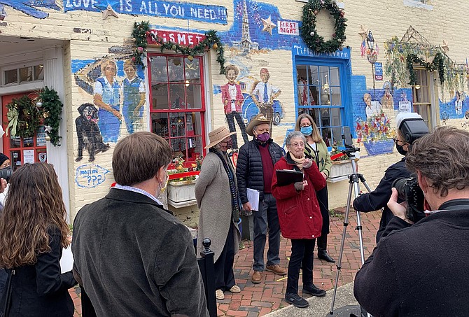 Nina Tisara, founder of the King Street Metro Enterprise Team, known as KSMET and the predecessor to the Old Town Business Association, makes remarks at the dedication of the Len Garon KSMET mural Dec. 4 at the corner of King and Fayette streets.