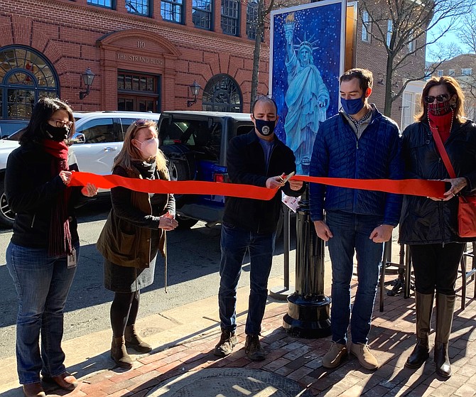 Mayor Justin Wilson, center, cuts the ribbon to kick off the Old Town Holiday Lamp Post Art Walk Dec. 5 on South Union St. With him are, from left, Deputy City Manager Emily Baker, Suzanne Bethel of The Art League, Boundary Properties CEO Ryan Fowler, and Charlotte Hall of the Old Town Business Association. The outdoor art display runs through Jan. 8 along King Street and selected side streets in Old Town.
