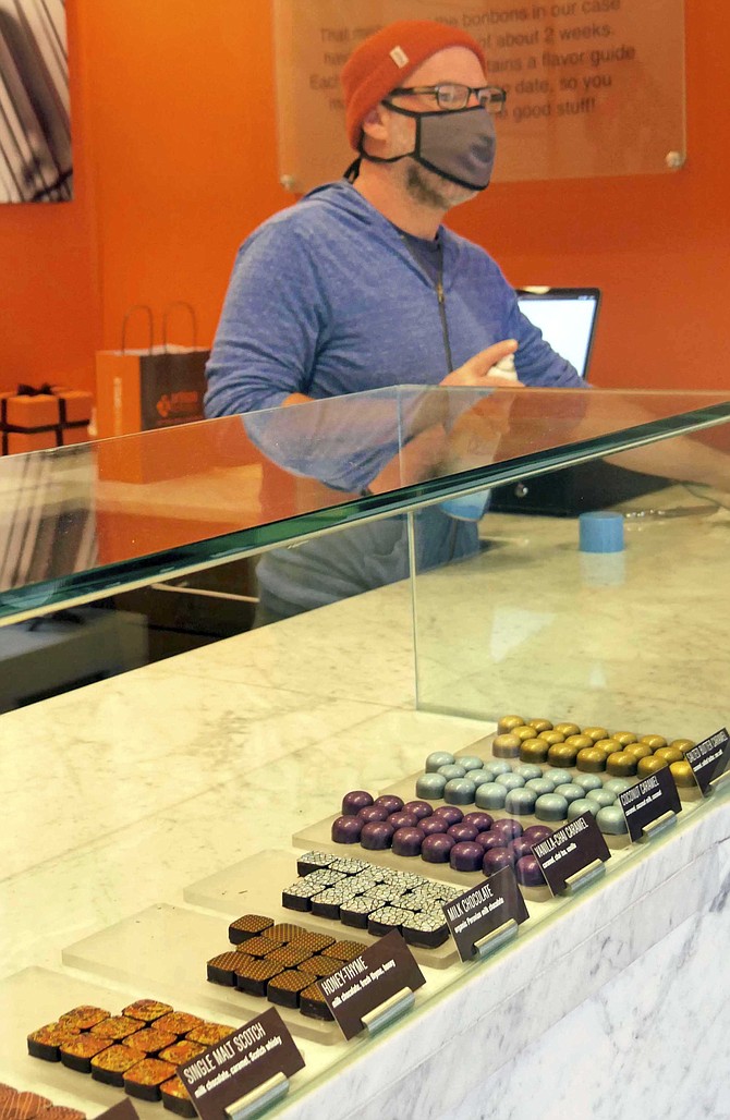 Jason Andelman, owner of Artisan Confections, waits on an in-store  customer at Artisan Confection on Fillmore Street in Arlington. He says that since the pandemic, the business has shifted dramatically to mail order deliveries.