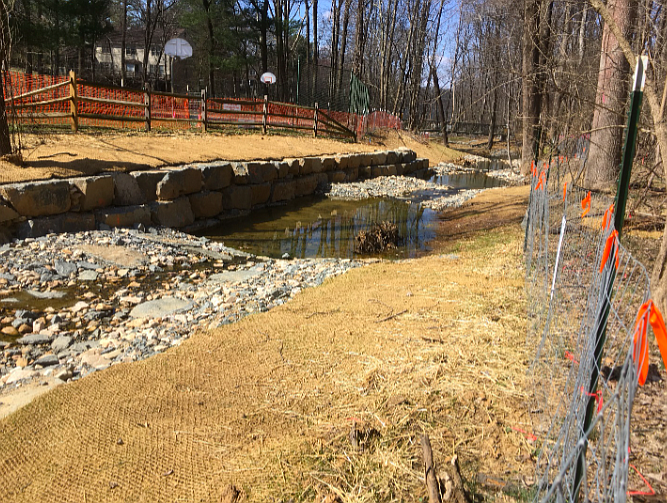 Fallsreach Restoration Project. A basketball court built in the floodplain was protected by armor-plating the stream bank. Note the total removal of plants and the newly engineered stream channel.