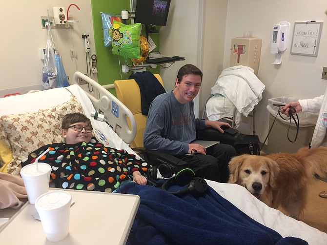 Gavin Smith of Great Falls and his dad, Keith, pictured during a canine visit at Johns Hopkins Children's Hospital. Mom Meg (not pictured) co-founded the nonprofit organization Cape Ivy.