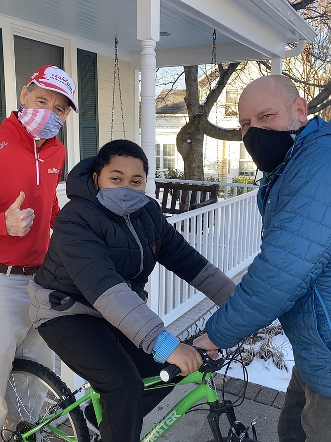 Bamilak Robi, 11, tries out his new bike, donated by the Green Lizard Foundation after someone stole his bike. Dave Meyer, co-owner of "The Lizard" (right)  and attorney Doug Landau, Abrams Landau Law Firm, Ltd., (left) make sure all is good with the bike and lock, as well as the helmet Landau donated through his Lids on Kids initiative.