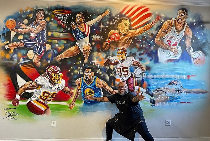 Famed artist DEZ Zambrano with his mural of star athletes.