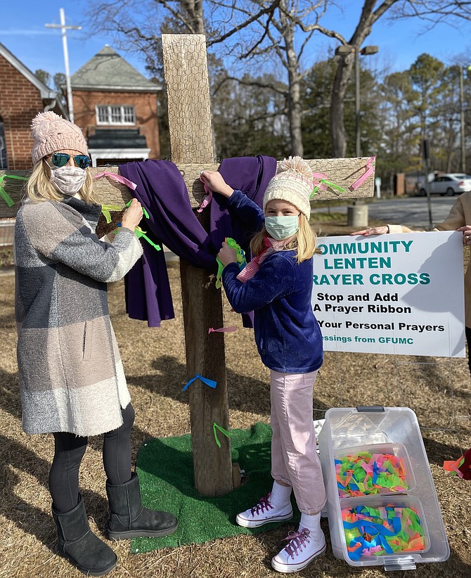 Sandra Musser and her daughter Caroline tie small ribbons noting their prayer intentions to the community Lenten Prayer Cross at United Methodist Church in Great Falls.