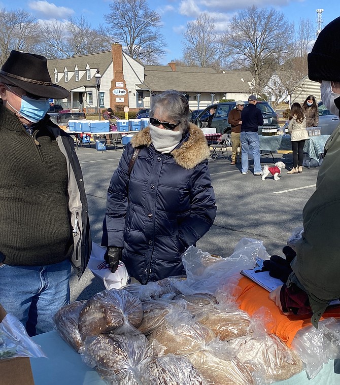 Elizabeth and David Hunt of Great Falls stop by the March 6 Great Falls Community Farmers Market and look over what to purchase from vendor Rustiq Bakery & Cafe of Historic Savage Mill, Md. Jonathan Steidel assists them with their selections.