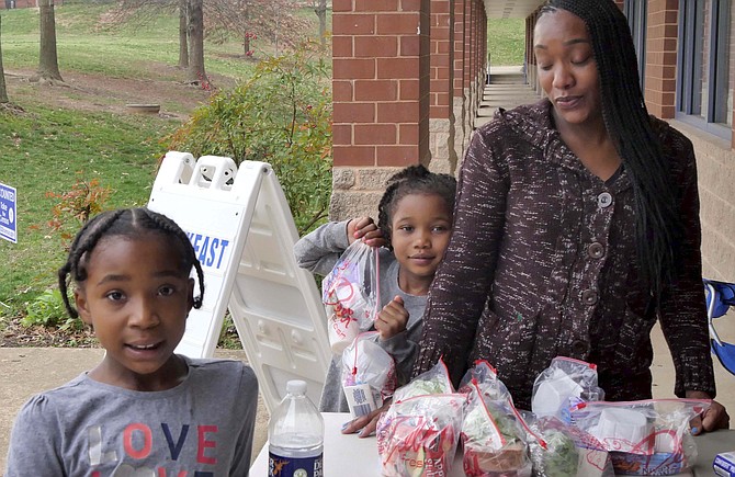 Children stop by Kenmore Elementary to pick up grab and go meals as feeding sites open outside schools to provide meals for school kids after schools close due to COVID.