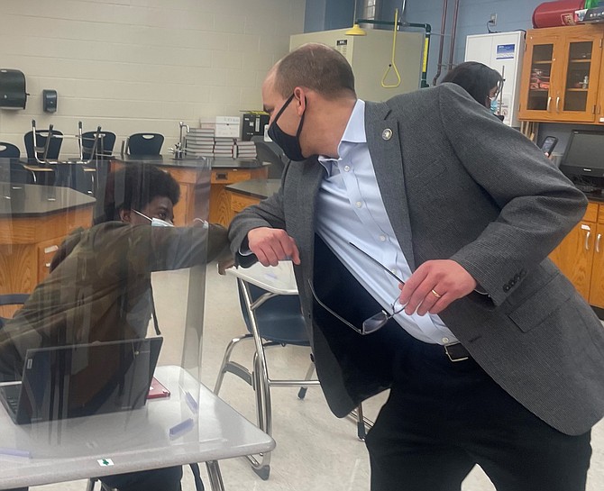 Alexandria Mayor Justin Wilson gives an elbow bump greeting to a student in the honors earth science class at T.C. Williams High School March 16.