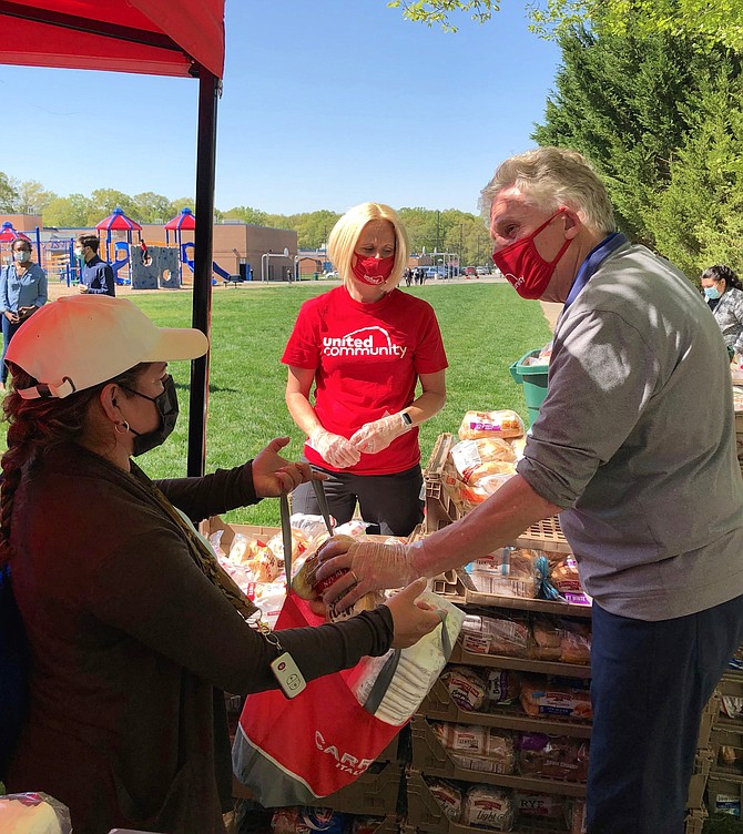 Former Virginia governor Terry McAuliffe, right, visits Mount Vernon Woods Elementary School April 20 during a United Community COVID relief food distribution event. McAuliffe is vying to win the Democratic nomination for governor on June 8.