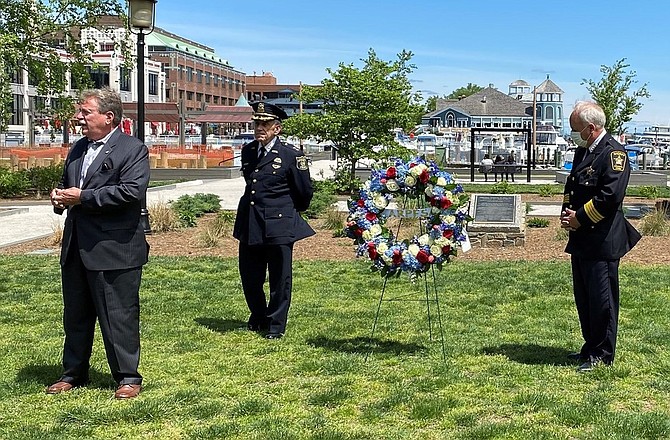 Jeremy Lenzer, President of the Alexandria Retired Police, Fire and Sheriff Association, left, makes remarks at the wreath laying ceremony at the Law Enforcement Memorial at Waterfront Park May 10 as Police Chief Michael Brown and Sheriff Dana Lawhorne look on.