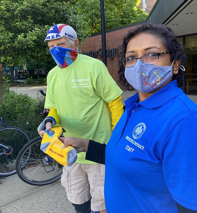 Shyamali Hauth, Hunter Mill District Staff, hands volunteer Bob Evans, senior W&OD Trail patroller and Tour de Hunter Mill ride marshal, a colorful pair of “Unity in Our Community” cycling socks, sure to step up the style of his cycling game.