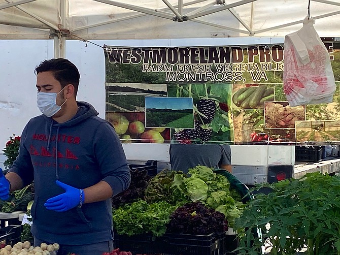 Francisco Becerra of Westmoreland Farms moves quickly, selling fresh produce, collards, asparagus, mushrooms, and plants at the vendor stand.