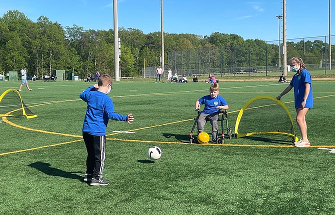 TOPSoccer players practice a drill together as the assigned TOPSoccer Buddy encourages them.