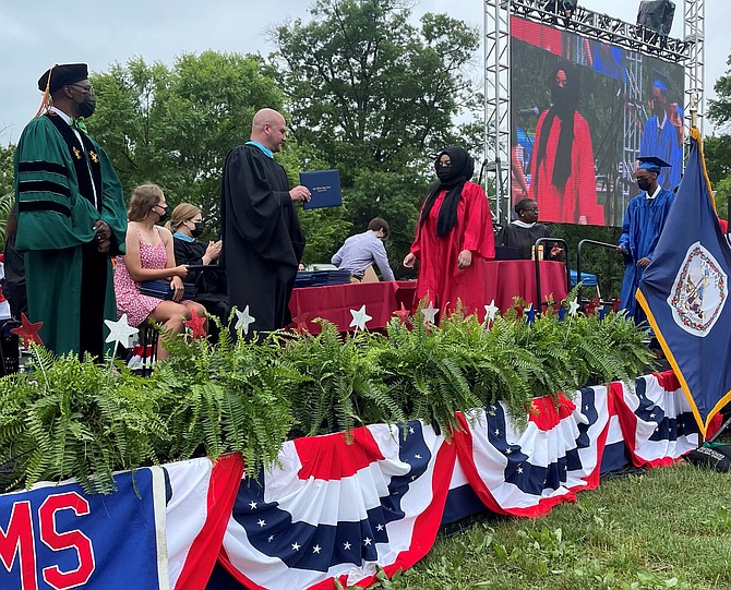 ACPS Superintendent Dr. Gregory Hutchings, left, and T.C. Williams High School principal Peter Balas present diplomas to the Class of 2021 during commencement ceremonies June 12 at Chinquapin Park.