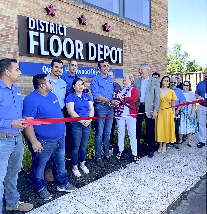 (Center) Managing Partner of District Floor Depot Yusef Mehmetoglu steadies the giant ribbon-cutting scissors with Town of Herndon Mayor Sheila Olem for the Ceremonial Grand Opening of the business after its soft-opening in the fall of 2020.