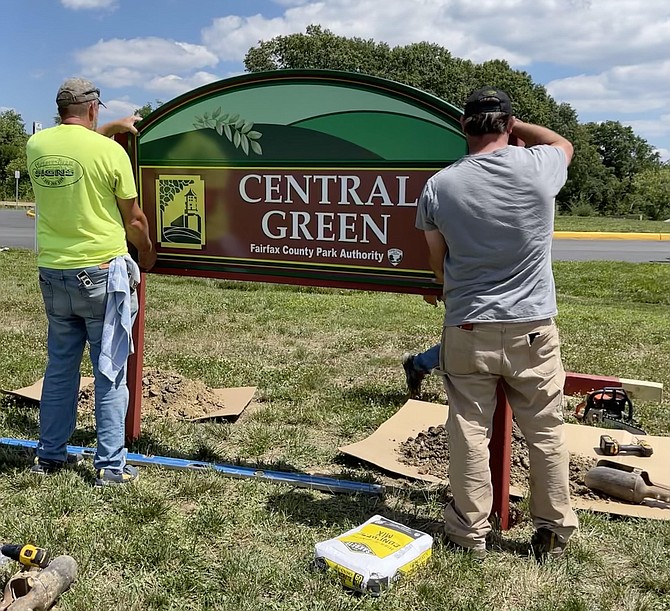 Contractors install signage identifying the new park with its distinctive logo recalling the area’s prior use as part of the Occoquan prison grounds.