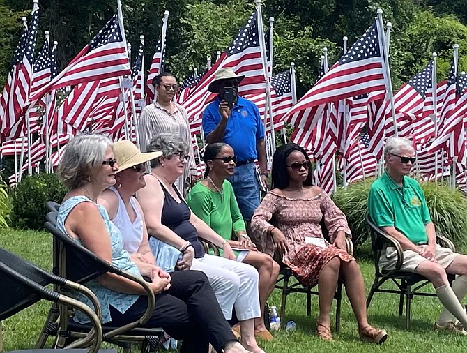 Attendees, including Campagna Center CEO Tammy Mann, third from right, listen to remarks at the opening ceremony of the Flags for Heroes display June 27 on the grounds of Cedar Knoll Restaurant. More than 250 flags are on display overlooking the Potomac River through July 11.