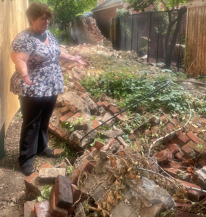 Lee-Fendall House Museum and Garden Executive Director Martha Withers stands among the rubble of the collapsed wall at the historic property.