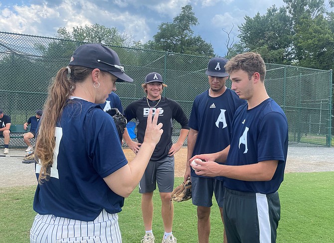 Coach Jennifer Hammond, left, demonstrates a pitching grip to the Alexandria Aces bullpen July 14 at Frank Mann Field.