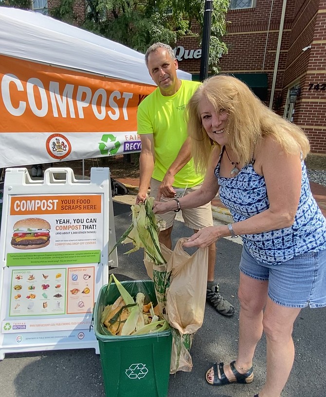 With a little assistance from Fritz Gottschalk of Veteran Compost, Sarah McGuire of Herndon drops her food scraps in the container at the Herndon Farmers Market location, one of four county markets selected to test the food scrap composting program.