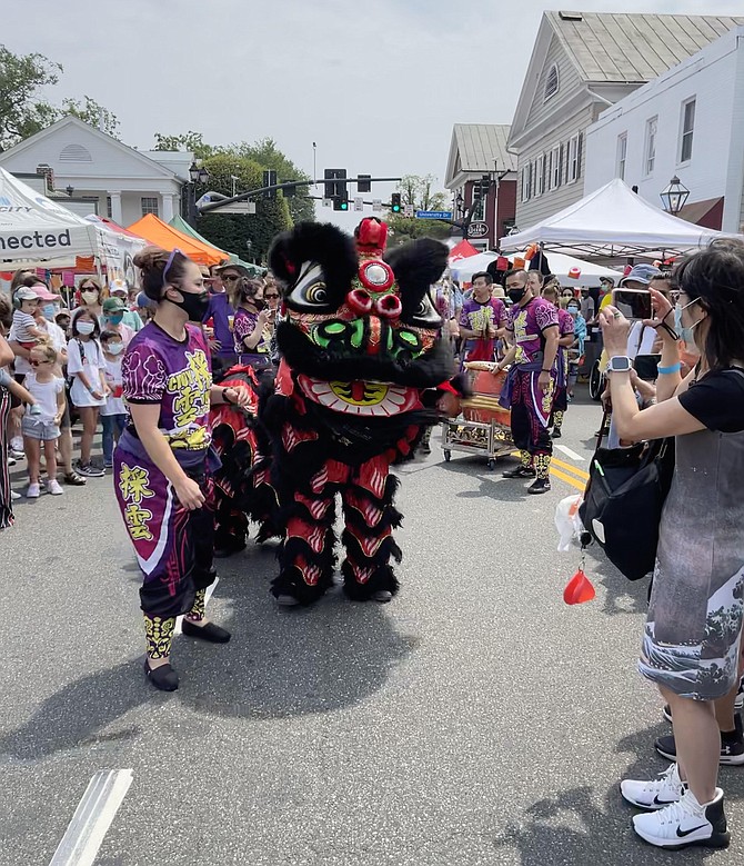 Chinese Lion dances up Main Street collecting tribute and head pats.