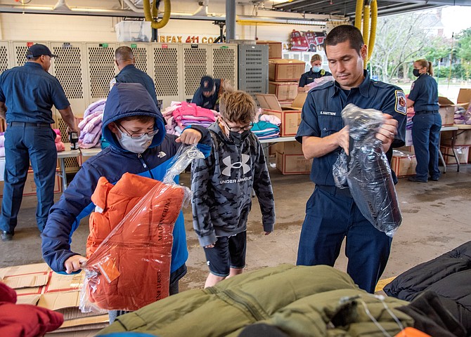 Firefighter Ken Savatttierri, right, is joined by his twin sons in helping prepare coats for distribution as part of the Firefighters and Friends annual coat drive Oct. 25 at Fire Station 11.