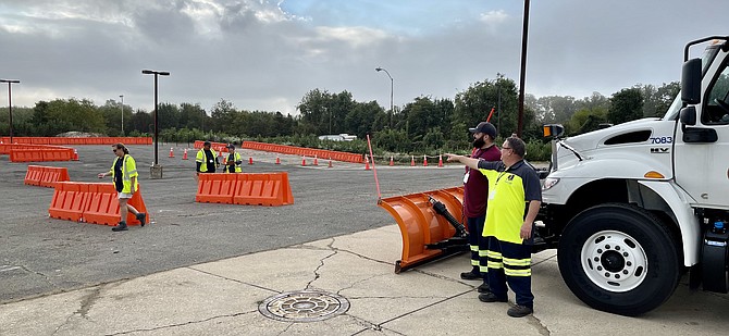 Scott Alwine (right) and Ensar Alibali, Heavy Equipment Operators, compare notes as judges make final course adjustments for the snow plow-dump truck event at the Road-E-O competition at the former Niki missile site in Lorton on Oct. 13.