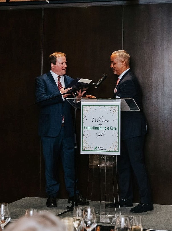 Garrett Golubn, left, is presented with the Arthritis Warrior award by emcee Shawn Perry at the Arthritis Foundation’s Commitment to a Cure Gala Oct. 28 at the District Winery.