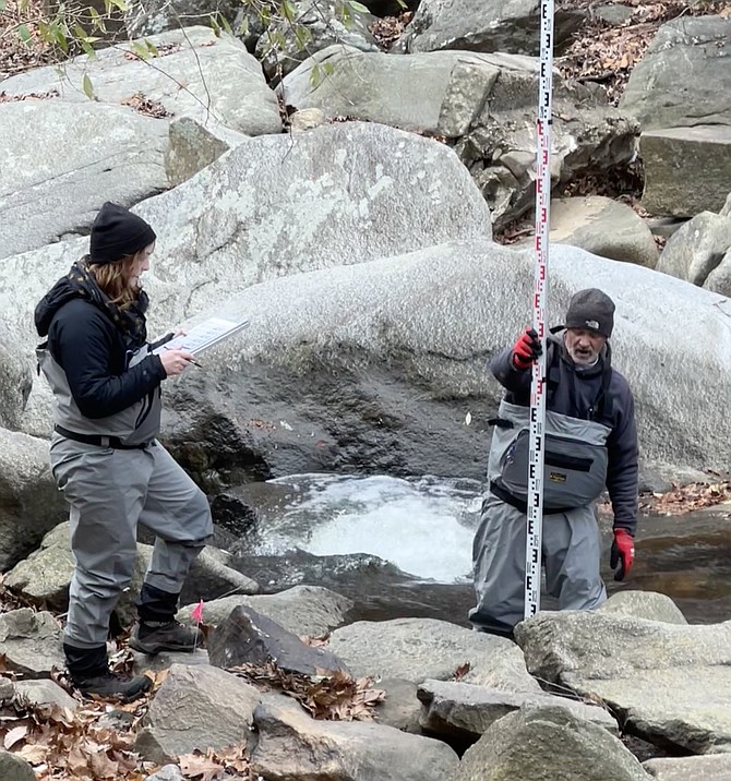 Jeff Tabot measures and calls out boulder depths as an indicator of stream habitat.