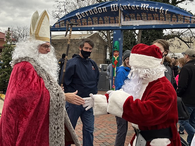 Saint Niklaus and Santa Claus reach out in holiday spirit at WinterMarkt 2021 held in the Town of Herndon and organized by the Dulles Regional Chamber of Commerce.