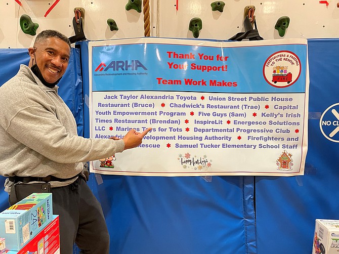 Firefighters and Friends to the Rescue founder Willie Bailey proudly shows off a banner thanking the sponsors of the annual toy drive Dec. 18 at Samuel Tucker Elementary School.