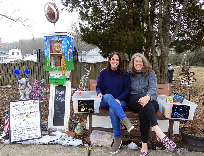 From left, Stephanie McCarthy and Janet Jaworski sit between the food-donation bins. At far left is Hugo, by the Little Free Library.